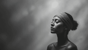A black and white portrait of a woman with closed eyes, wearing a headband and facing sideways. Soft lighting highlights her calm expression, subtly reflecting the science behind meditation. The blurred background enhances the tranquil effect.